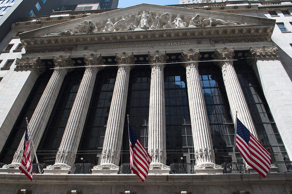 The columned front of the New York Stock Exchange building with American flags