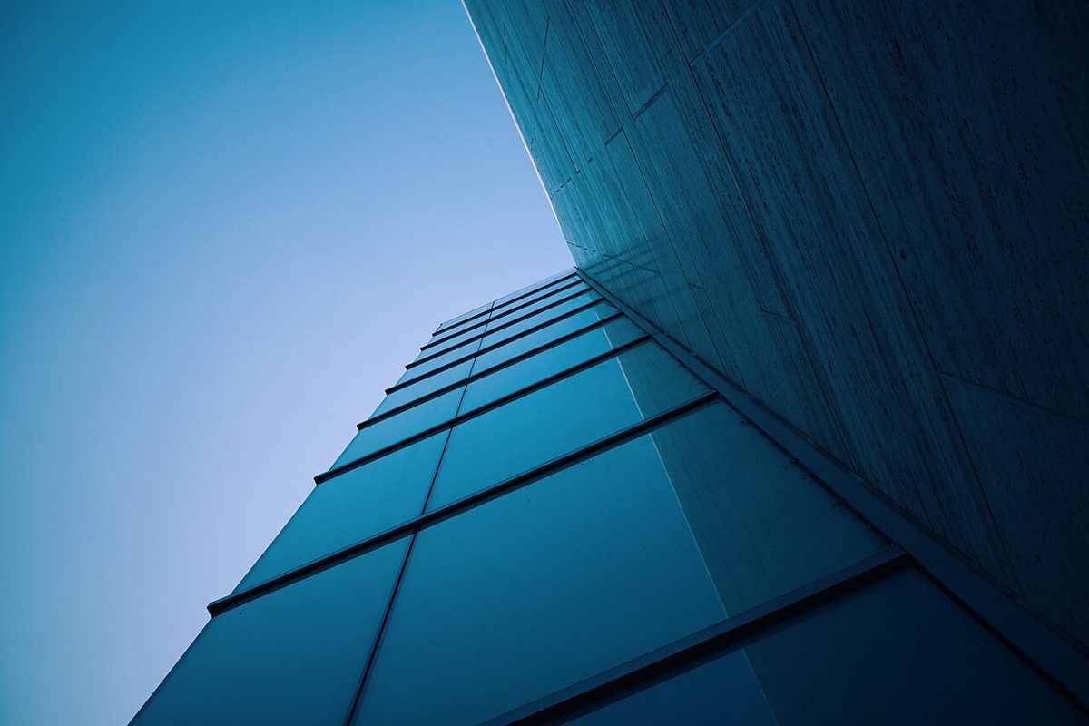 The glass corner of a tall office building against a blue sky