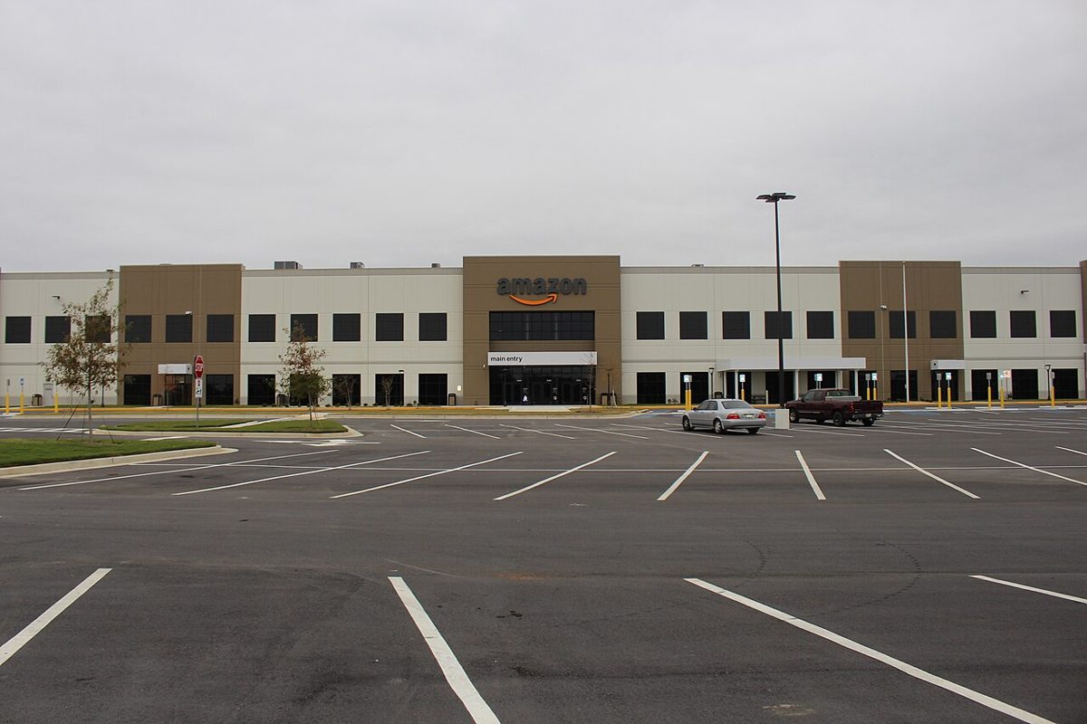 A large Amazon fulfillment center building in Macon, Georgia, with a parking lot in front